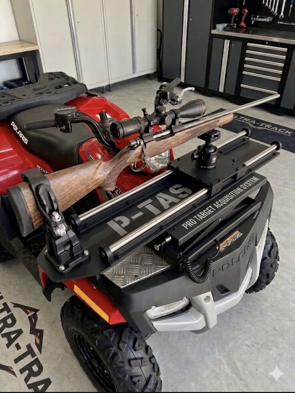 A production P-TAS in matte black mounted on the front rack of a red Polaris quad bike, carrying a scoped rifle, with each part numbered